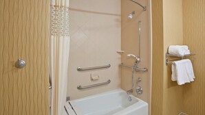 A modern bathroom with a bathtub, grab bars, a showerhead, and a towel rack.