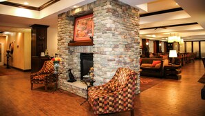 A lobby with a stone fireplace, two armchairs, a coffee table, and a dining area with tables and chairs. - Hampton Inn Matamoras/Milford (Matamoras)