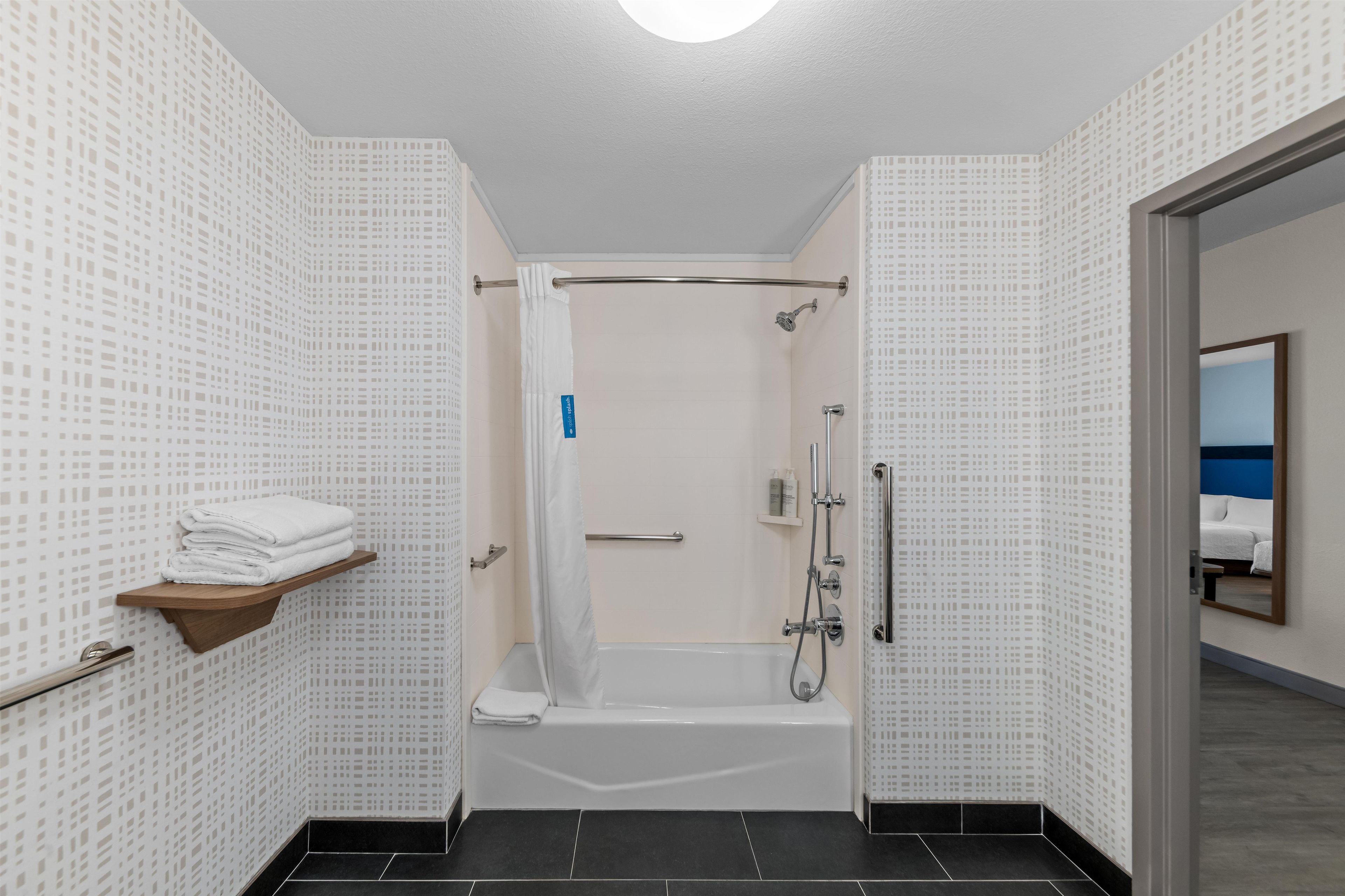 A bathroom with a shower, toilet, and a towel rack.