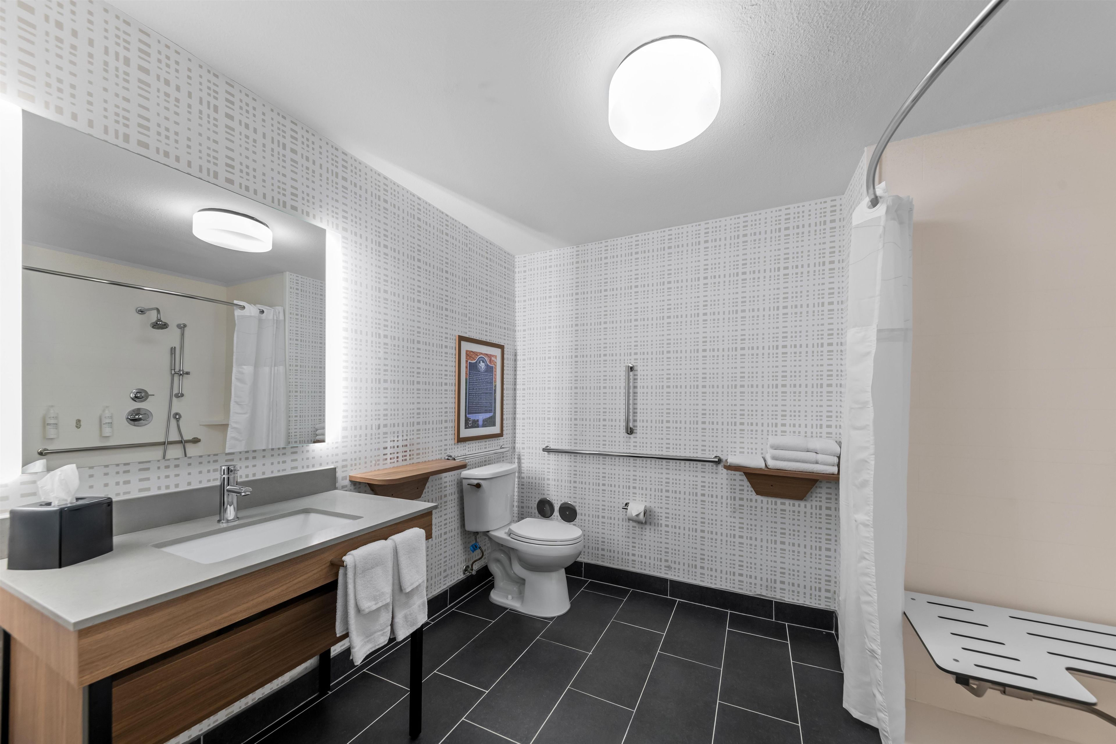 Une salle de bain moderne avec un grand miroir, un lavabo, des toilettes et un espace douche.