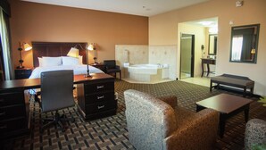 A hotel room with a bed, desk, chair, sofa, and a bathroom with a bathtub. - Hampton Inn & Suites Palestine (Palestine)