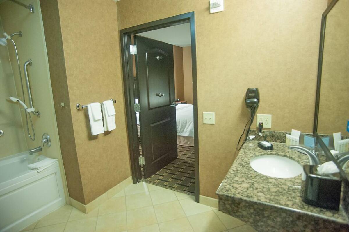 A hotel bathroom with a shower, a sink, and a towel rack.