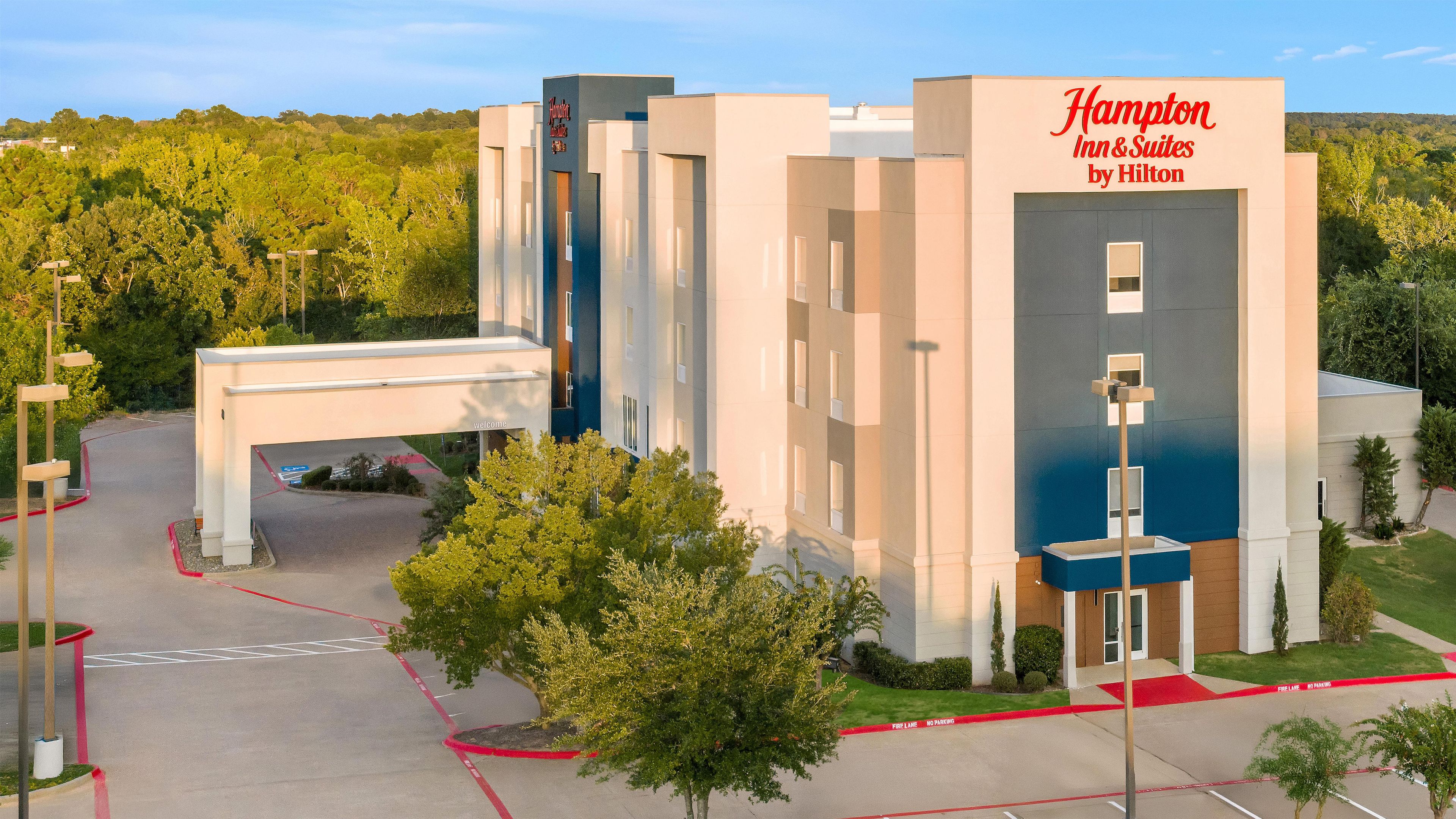 Un hotel moderno con un letrero visible de Hampton Inn & Suites by Hilton.