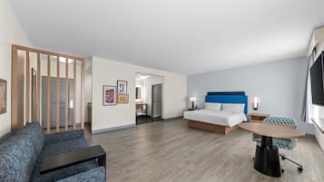 Una camera d'albergo moderna con un letto, un divano, un tavolino e una TV.