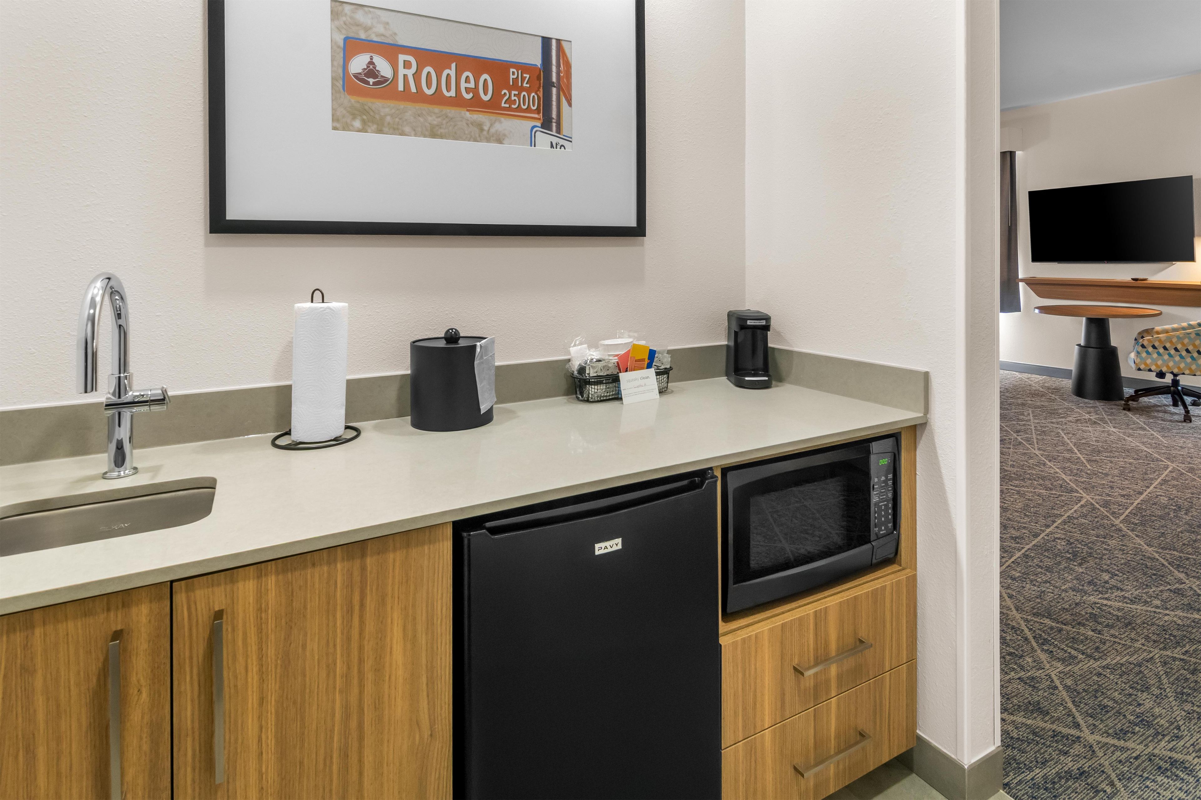 Bany d'hotel amb un lavabo, paper higiènic, una cafetera i un gresol.