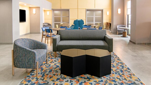 A modern hotel lobby with a grey sofa, patterned armchair, and a central coffee table. - Hampton Inn and Suites Fort Worth/Forest Hill (Fort Worth)