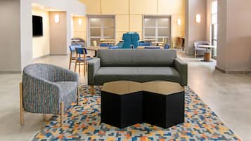A modern lobby with a sofa, chairs, a coffee table, and a patterned rug.