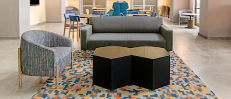 A modern lobby with a sofa, chairs, a coffee table, and a patterned rug.