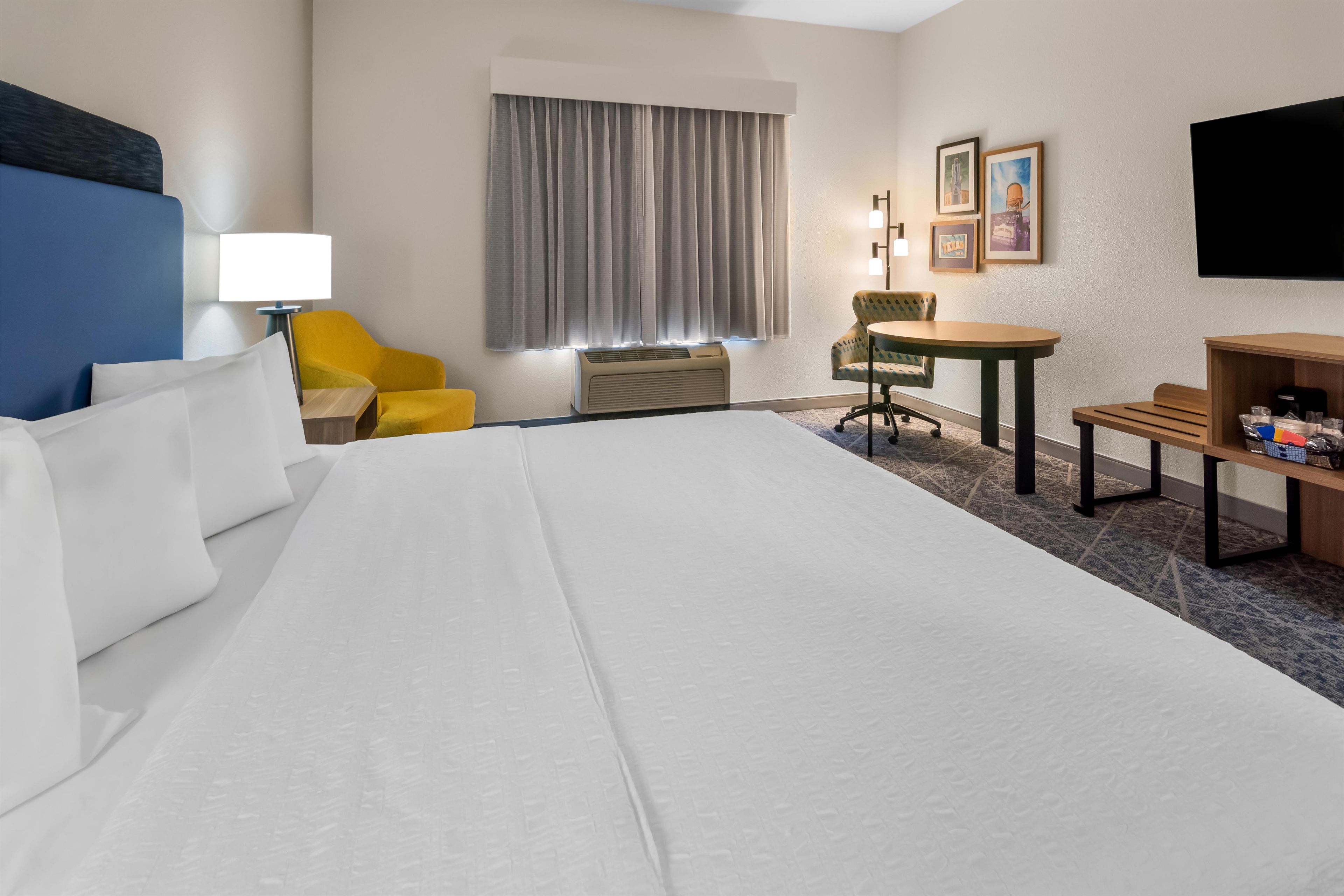 Een hotelkamer met een groot bed, een bureau, een stoel, een tafel en een televisie.