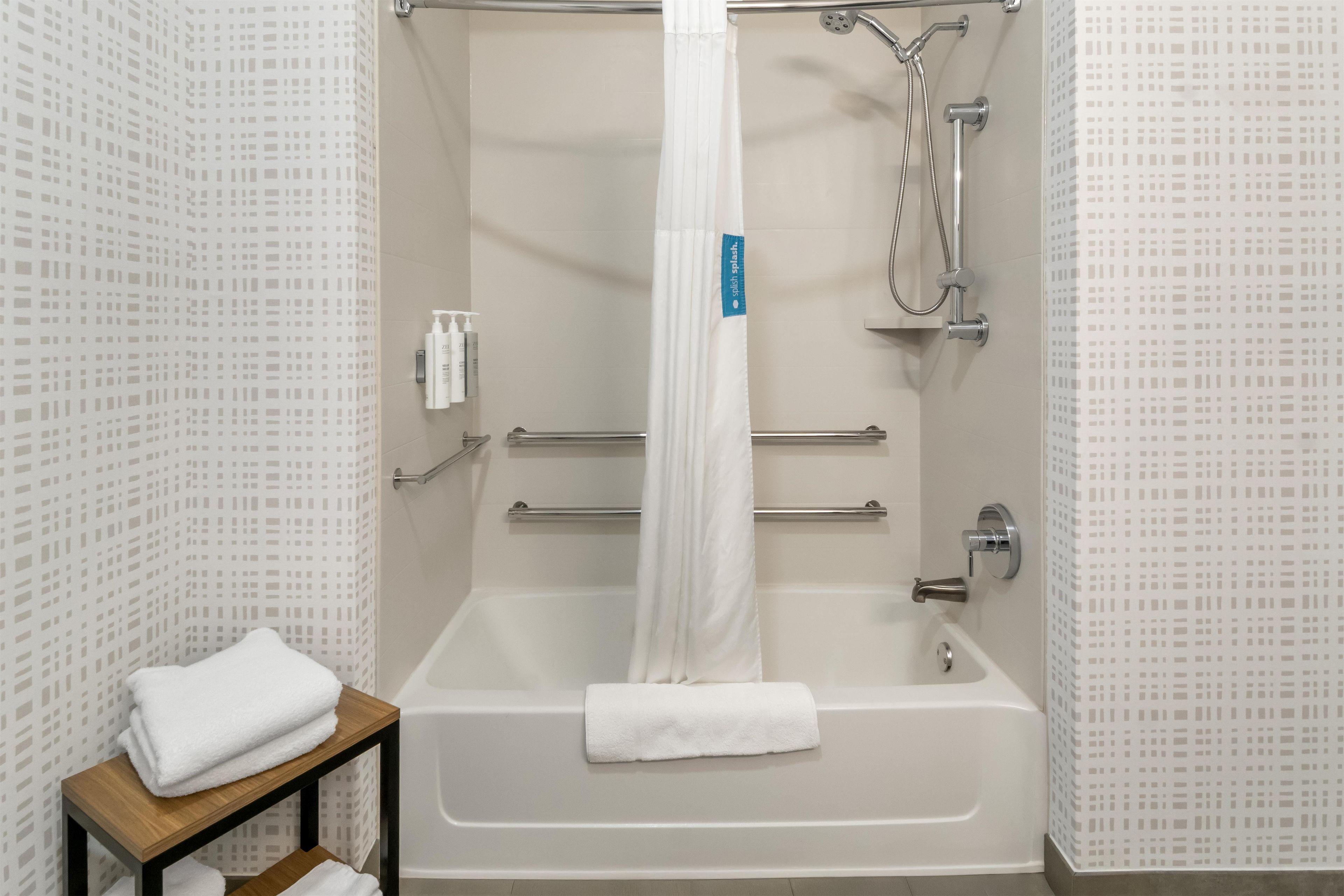 A bathroom with a bathtub, shower, and a towel rack.