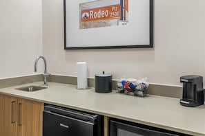 A hotel kitchen with a sink, a paper towel dispenser, a coffee maker, and a trash can. - Hampton Inn and Suites Fort Worth/Forest Hill (Fort Worth)