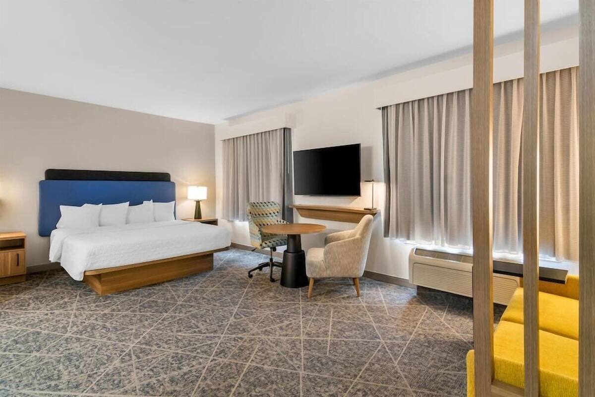 Une chambre d’hôtel comprenant un lit, un bureau, une chaise, une télévision et un canapé.