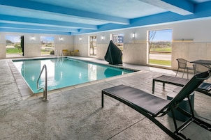 A swimming pool with a view of the outdoors, a covered seating area, and a table with chairs.