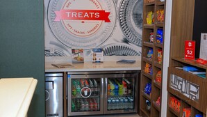 A vending area with a 'TREATS' sign, a refrigerator stocked with beverages, and shelves with snacks and souvenirs. - Hampton Inn Atlanta-Canton (Canton)