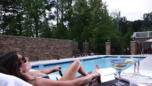 A person relaxing by a poolside lounge chair with a drink on the table. - Hampton Inn Atlanta-Canton (Canton)