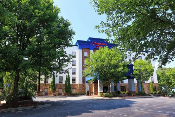 A Hampton Inn with a brick facade, large windows, and a parking lot.