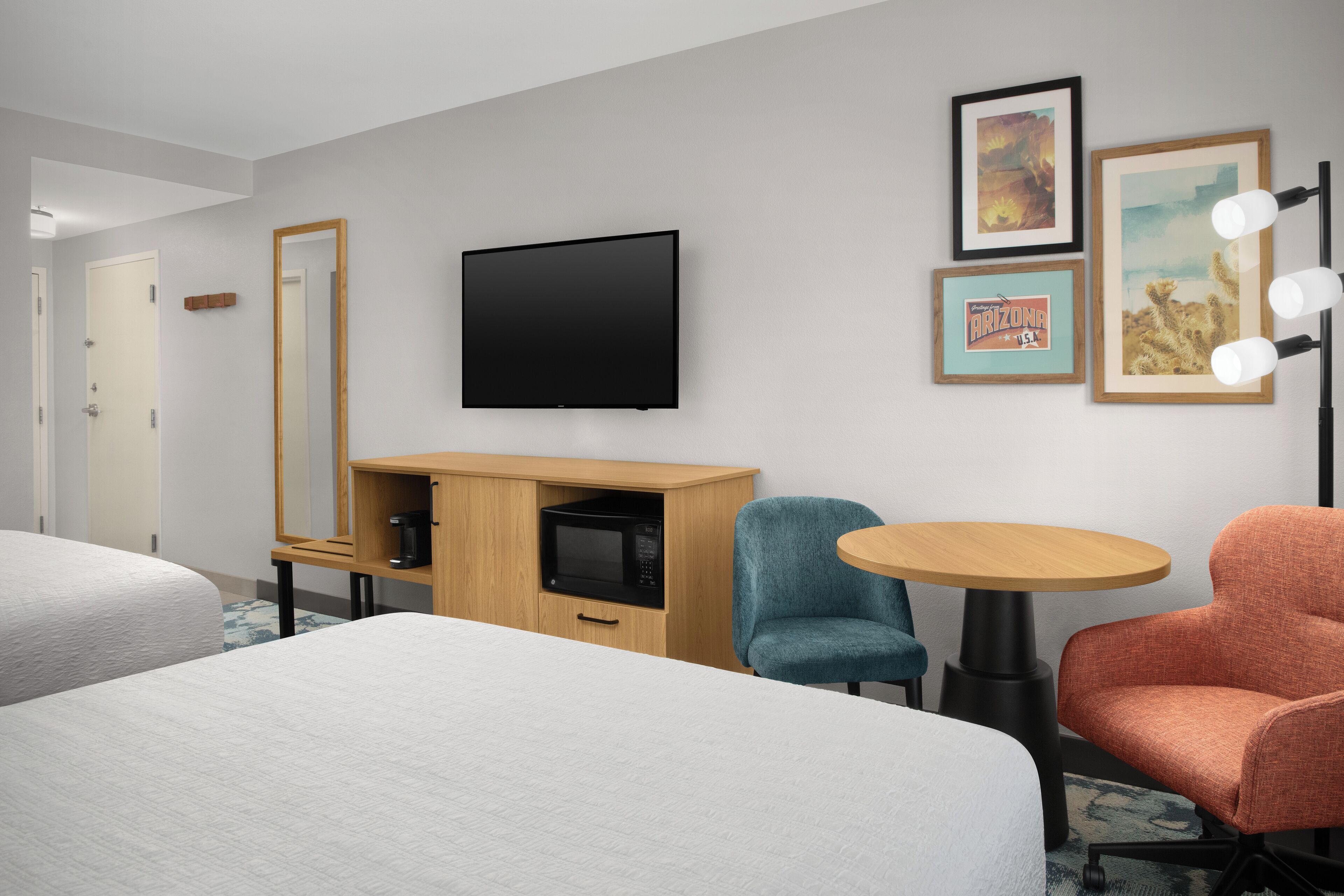 Habitación de hotel con cama, escritorio con microondas, televisor y dos sillas.