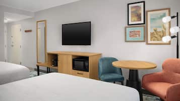 Habitación de hotel con cama, escritorio con microondas, televisor y dos sillas.