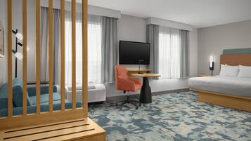 A hotel room with a bed, a desk with a chair, a television, and a window with curtains.