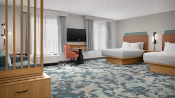Ein Hotelzimmer mit Bett, Schreibtisch mit Fernseher, Stuhl, Kleiderschrank und einem großen Fenster mit Vorhängen.