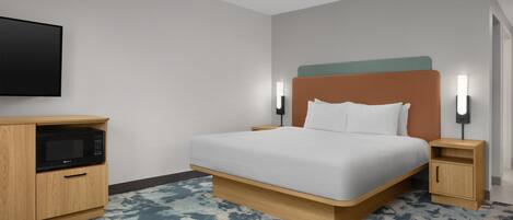 A hotel room with a bed, a TV, a microwave, and a nightstand.