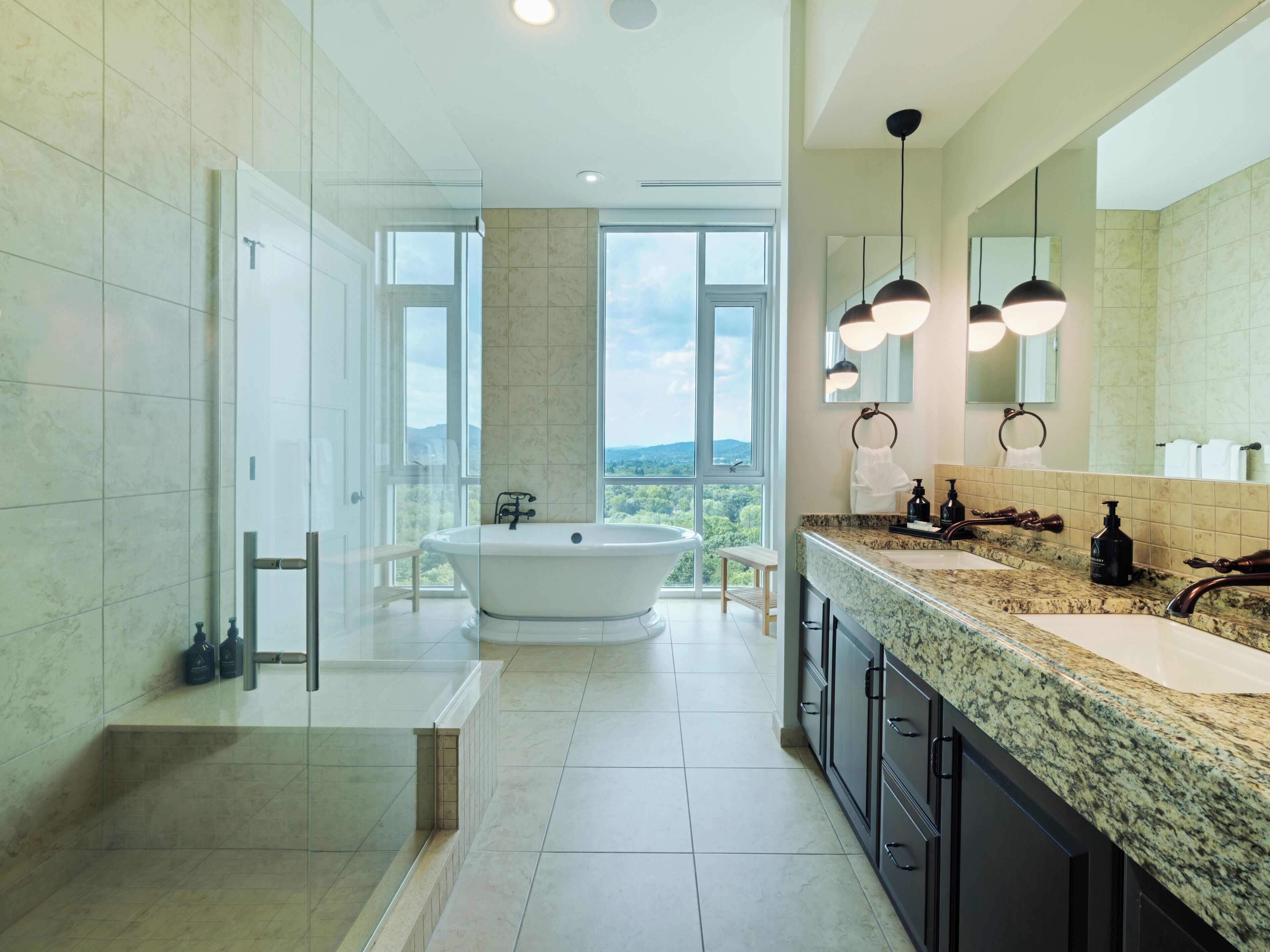 A modern bathroom with a freestanding bathtub, a large mirror, and a granite countertop.