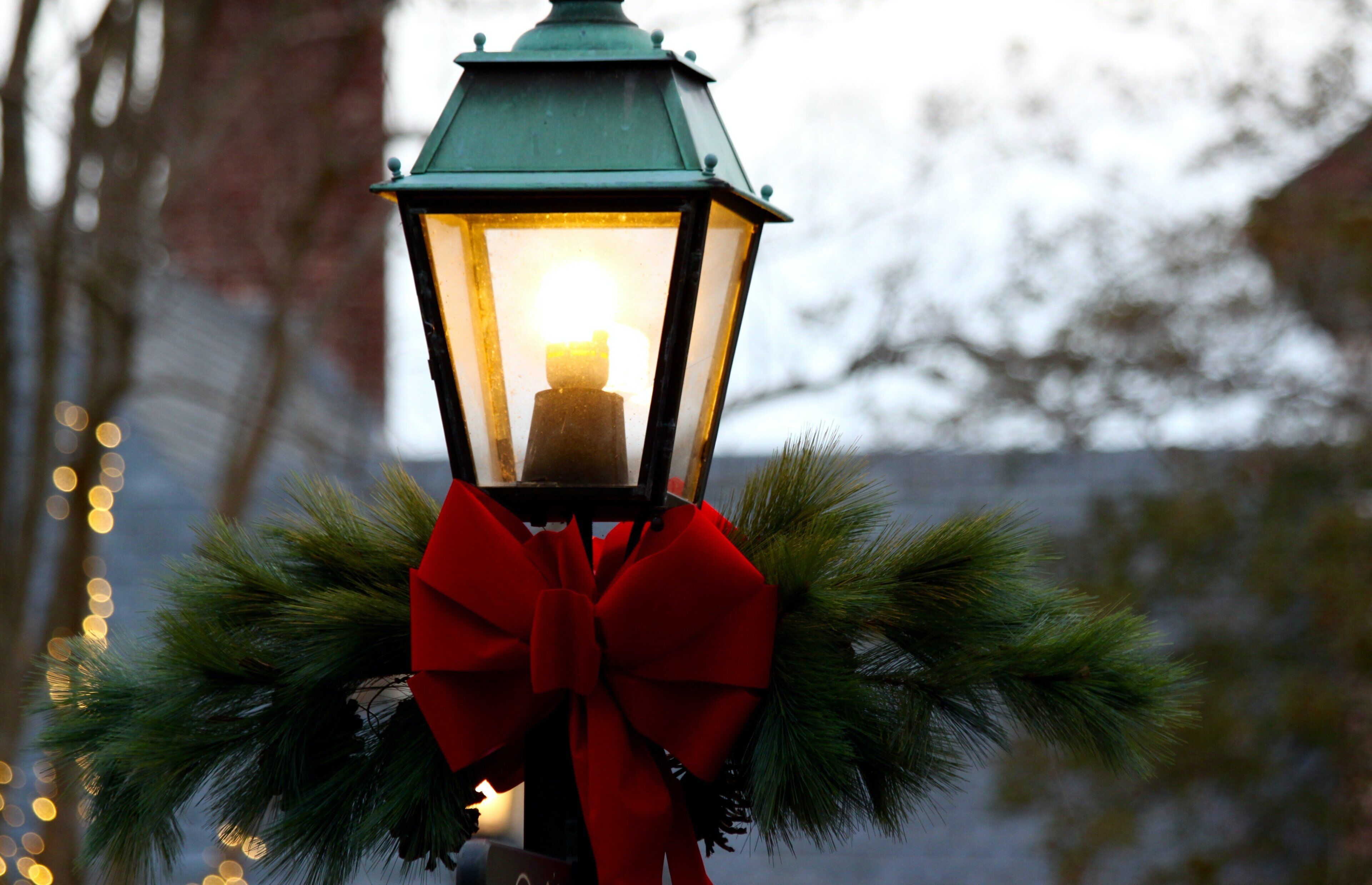 A lantern with a red bow and pine branches.