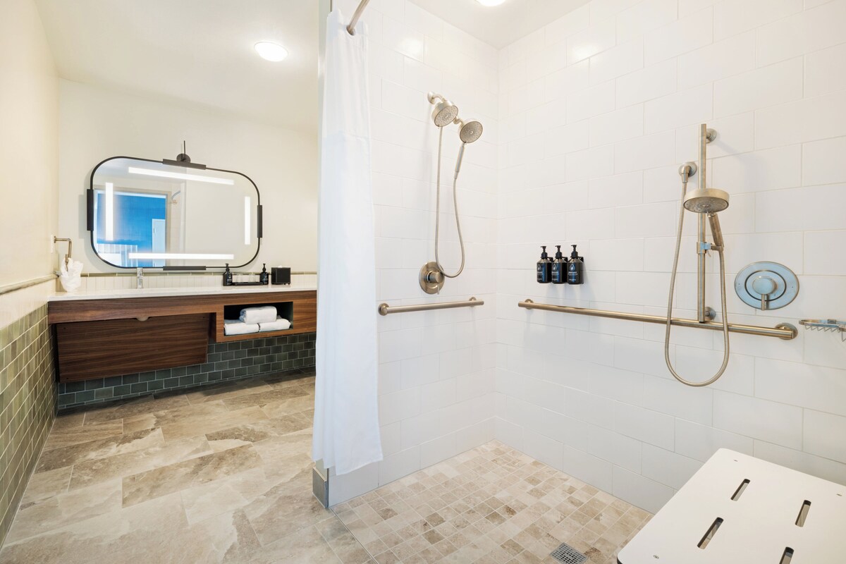 A modern bathroom with a shower, a vanity with a mirror, and a towel rack.