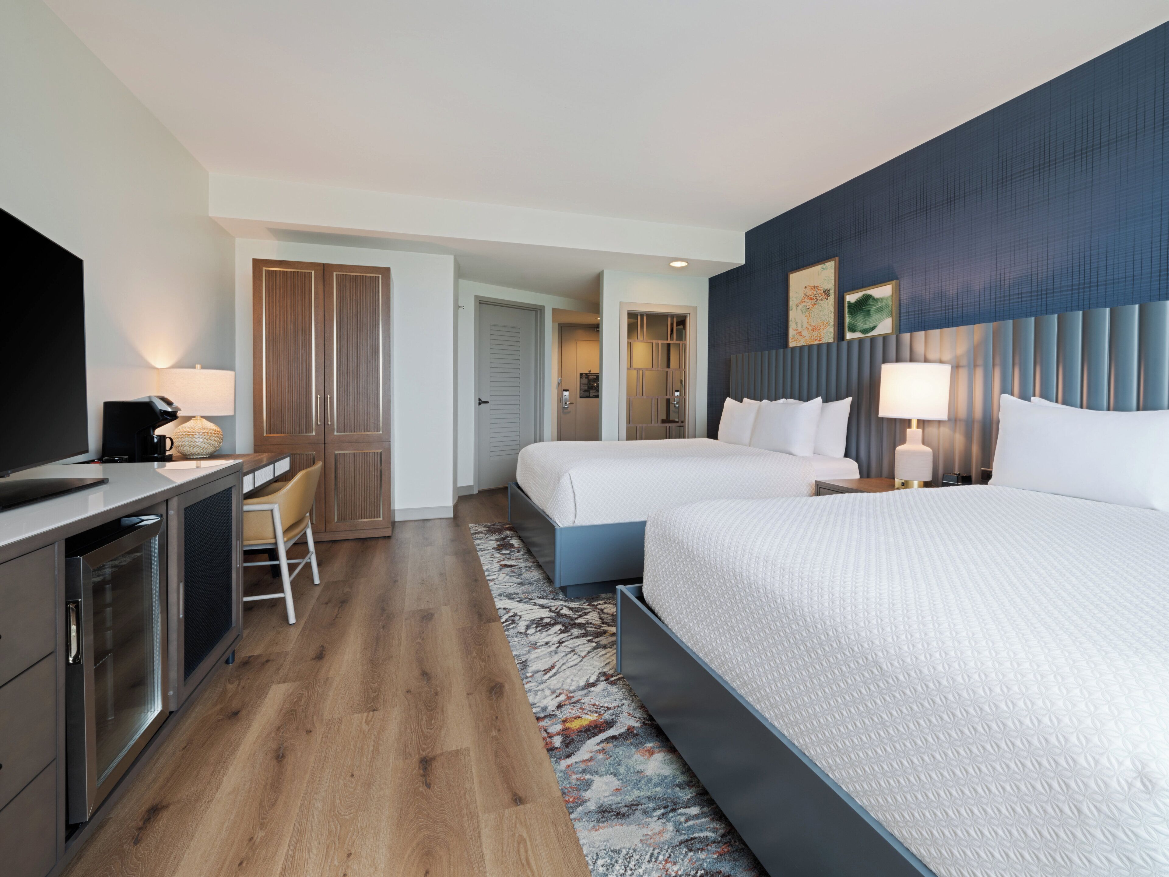 A hotel room with a bed, a desk, a chair, a TV, and a bathroom.