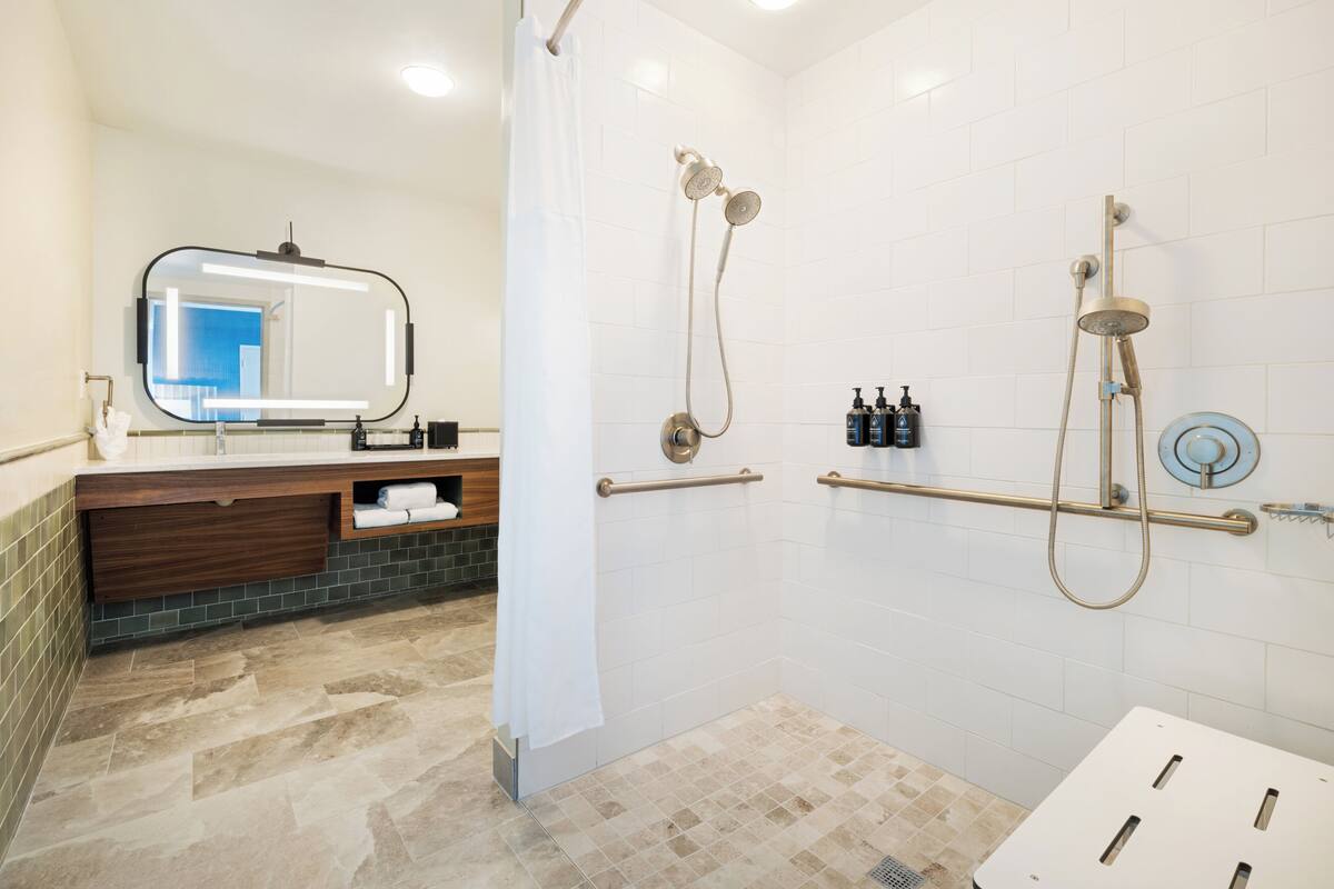 A modern bathroom with a shower, a vanity with a mirror, and a towel rack.