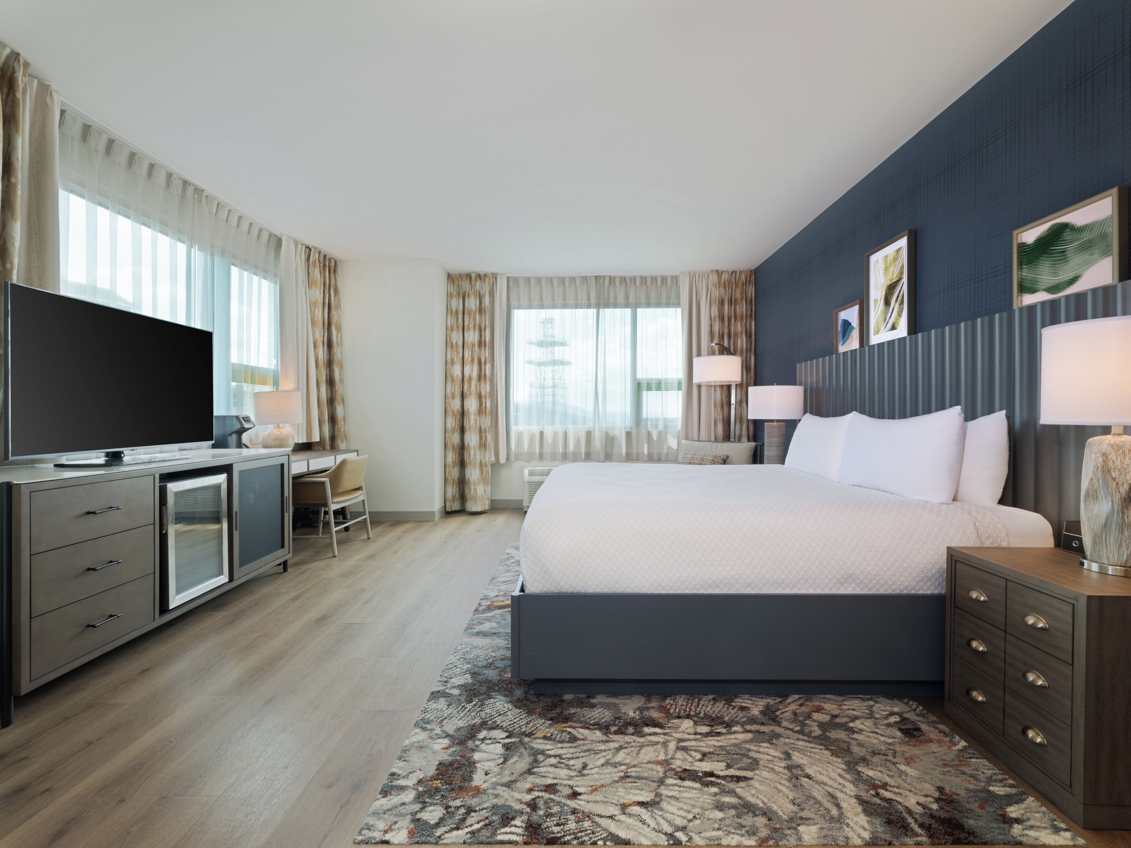 Een moderne hotelkamer met een groot bed, een bureau, een televisie en uitzicht op de stad.