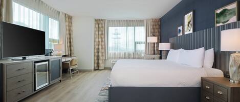 Een moderne hotelkamer met een groot bed, een bureau, een televisie en uitzicht op de stad.