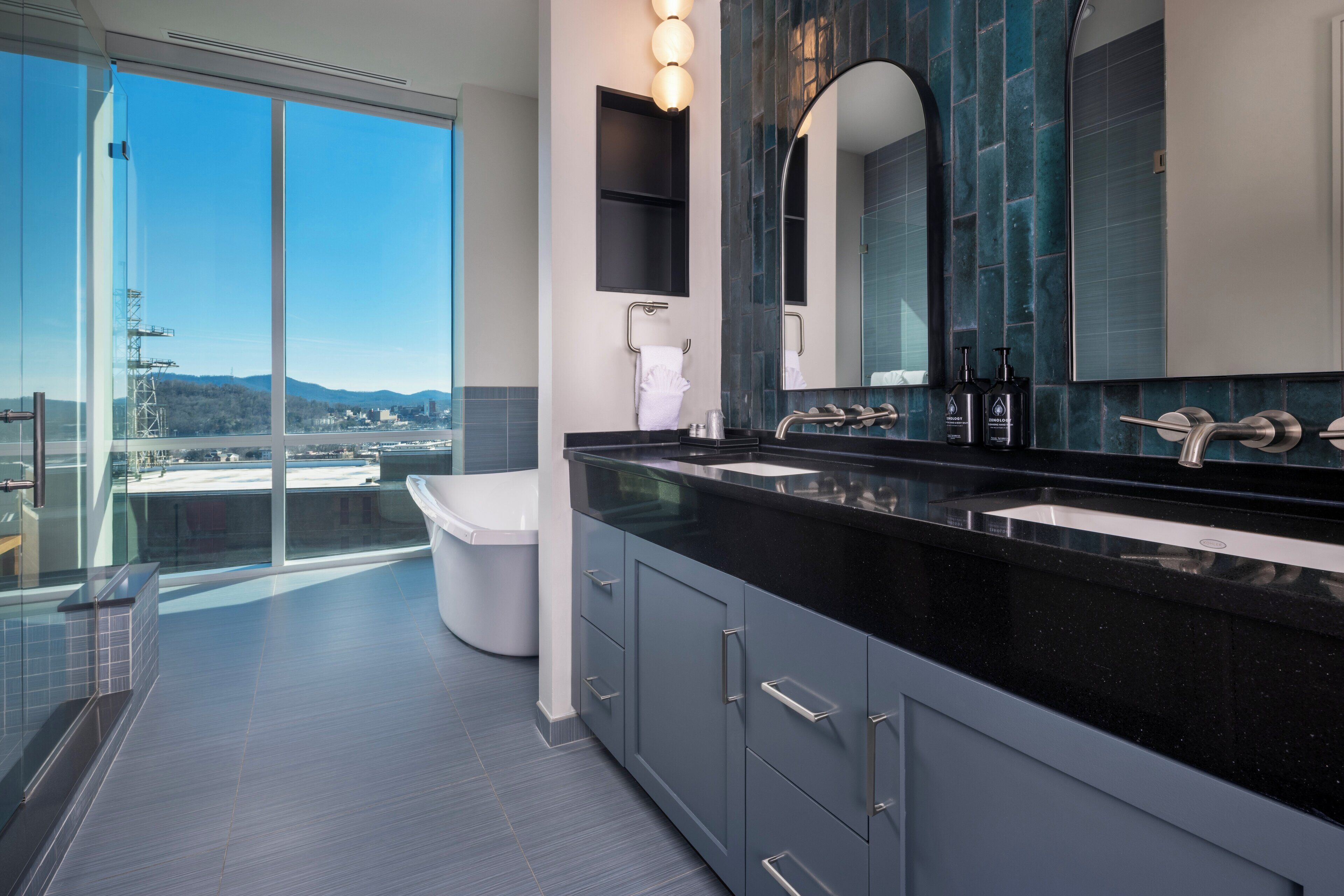 A modern bathroom with a large mirror, two sinks, and a toilet.