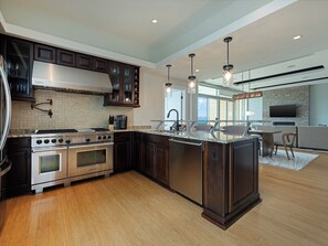 A modern kitchen with dark wood cabinets, stainless steel appliances, and a large island.