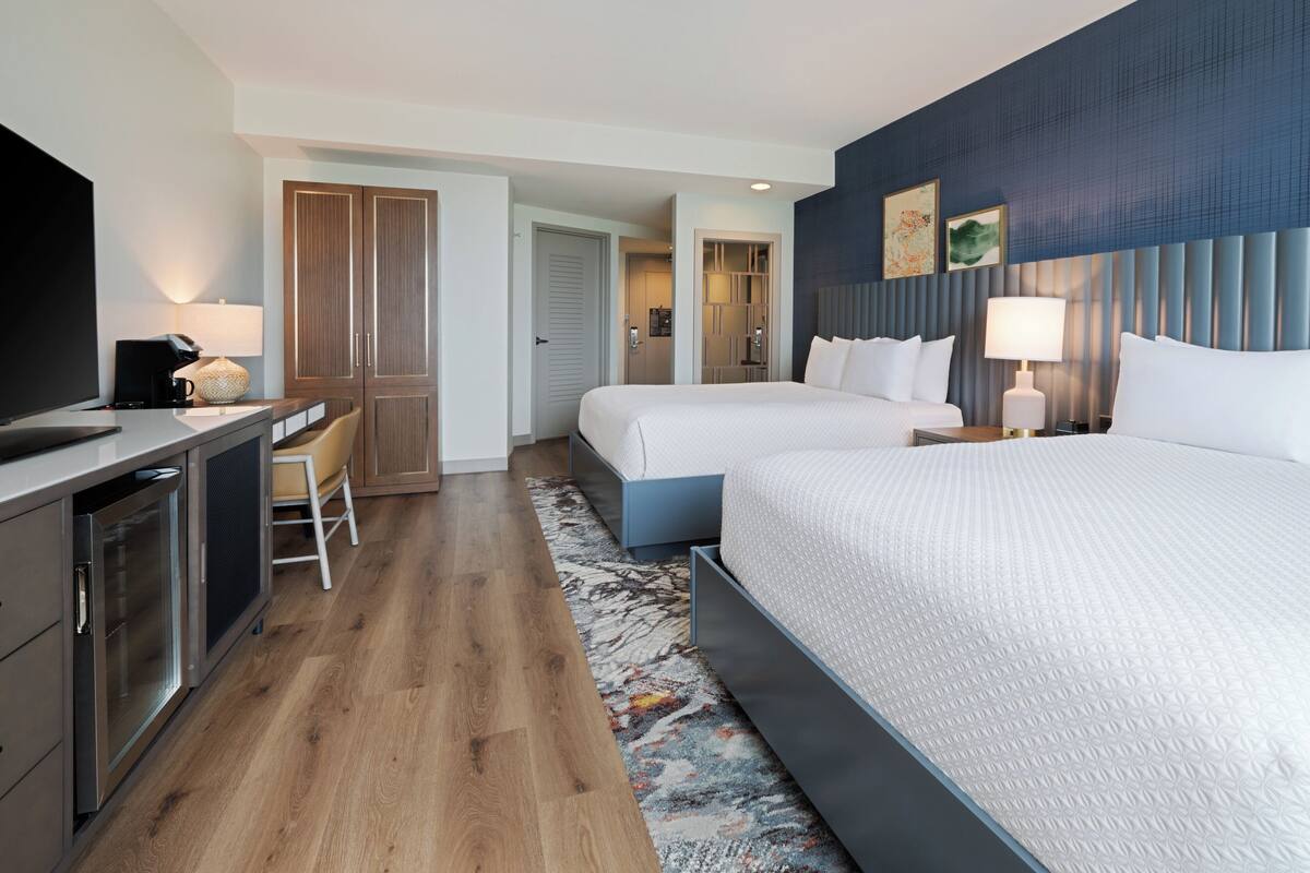 A hotel room with a bed, a desk, a chair, a TV, and a bathroom.