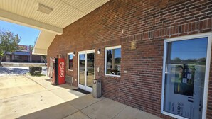 A brick building with a Coca-Cola vending machine, a large window advertising UHD 4K TV, and a clear sky. - Deerfield Inn McComb I-55 (McComb)