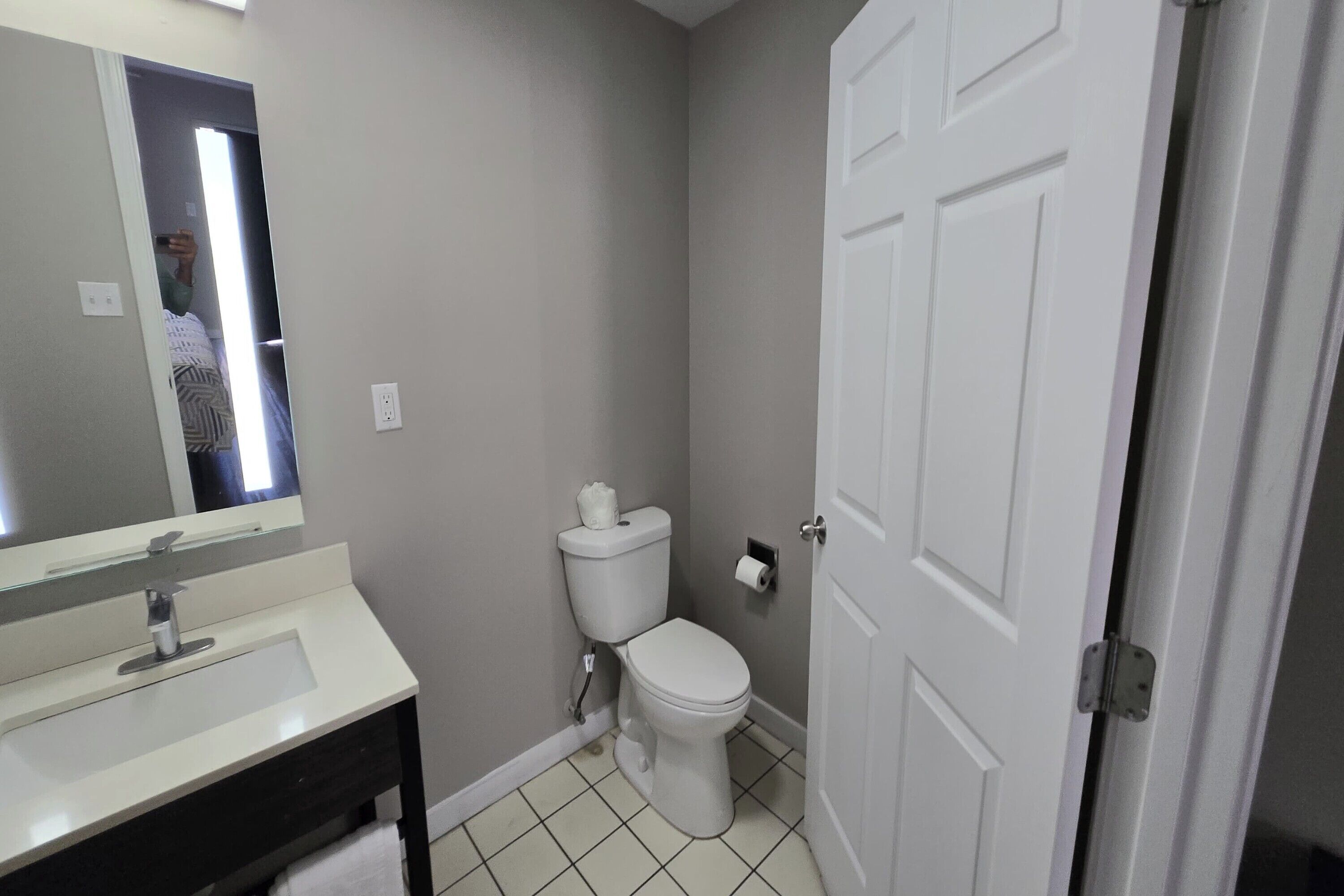 Baño con lavamanos, inodoro y puerta blancos.