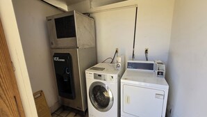 A laundry room with a front-loading washer, a top-loading dryer, and an air conditioning unit. - Deerfield Inn McComb I-55 (McComb)