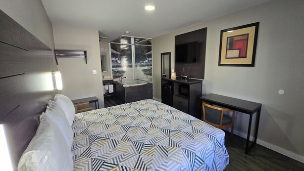 A hotel room with a bed, a desk, a chair, a TV, and a bathroom with a shower and sink. - Deerfield Inn McComb I-55 (McComb)