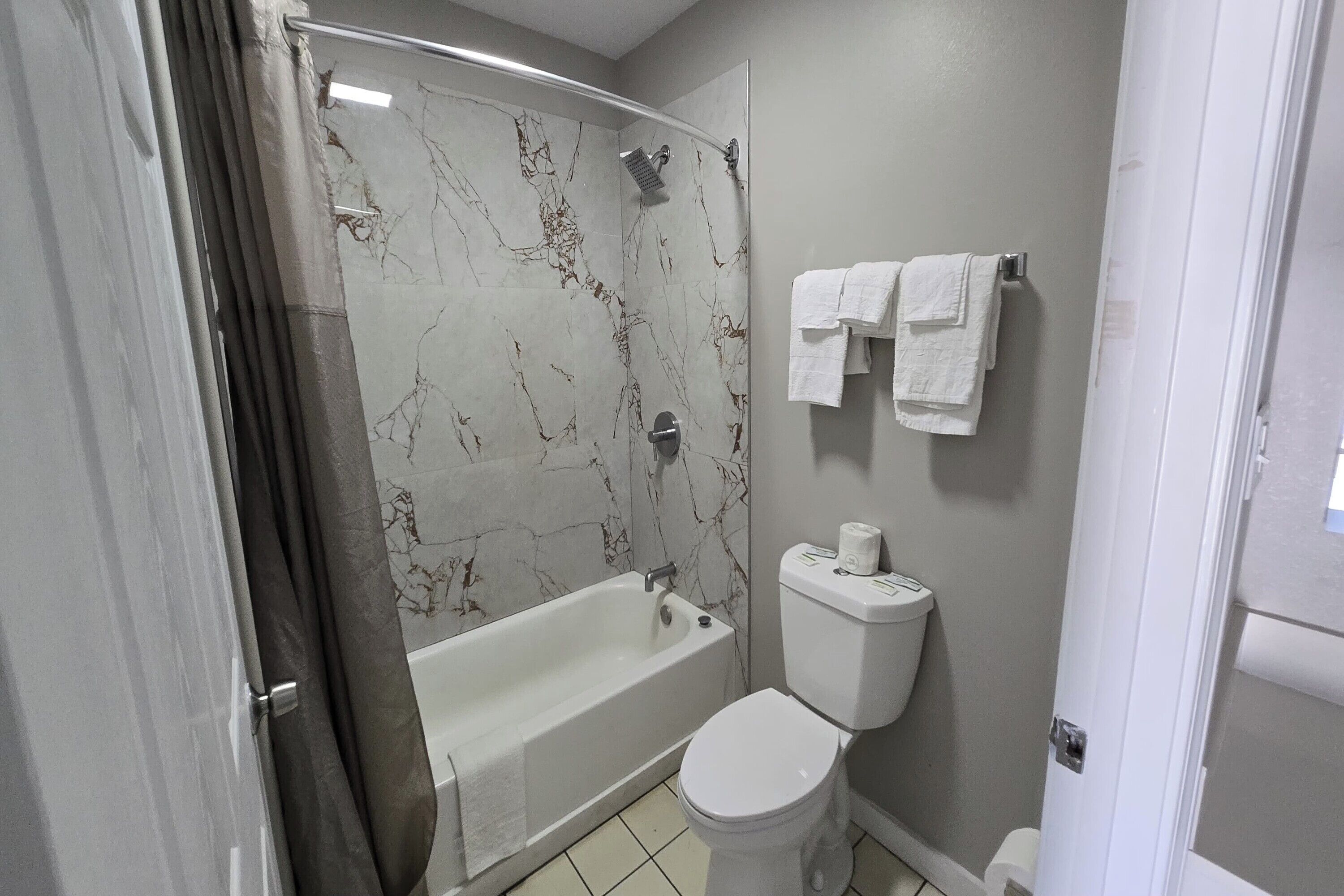 A bathroom with a bathtub, toilet, and shower curtain.
