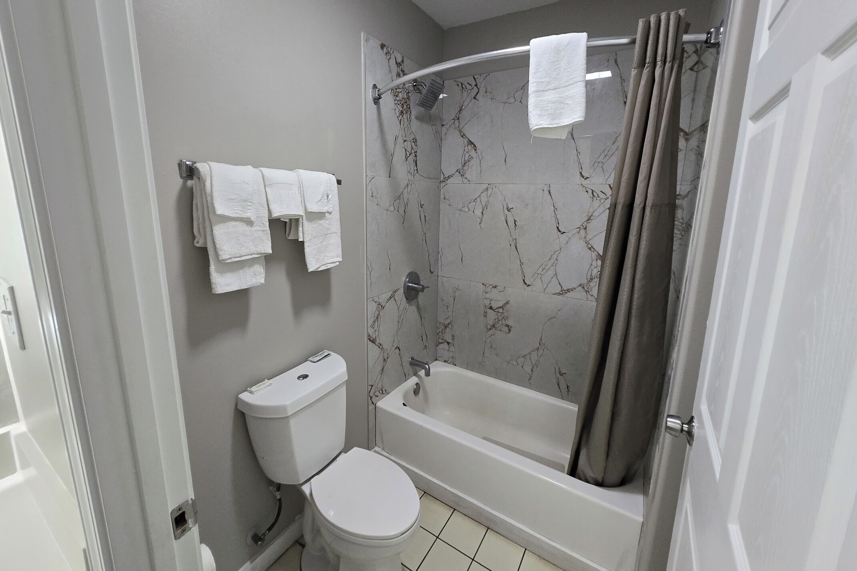 Un bagno con toilette, vasca e tenda per la doccia.