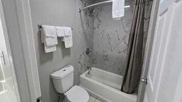 Un bagno con toilette, vasca e tenda per la doccia.