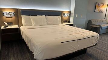 A hotel room with a large bed, two bedside tables, a chair, and a wall-mounted artwork.