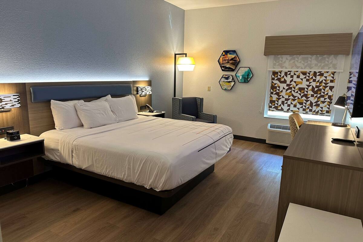 Ein Hotelzimmer mit einem großen Bett, Nachttischen, einem Schreibtisch und einem Sessel.