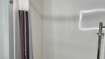 A modern bathroom with a glass-enclosed shower, a white bathtub, and a striped shower curtain.