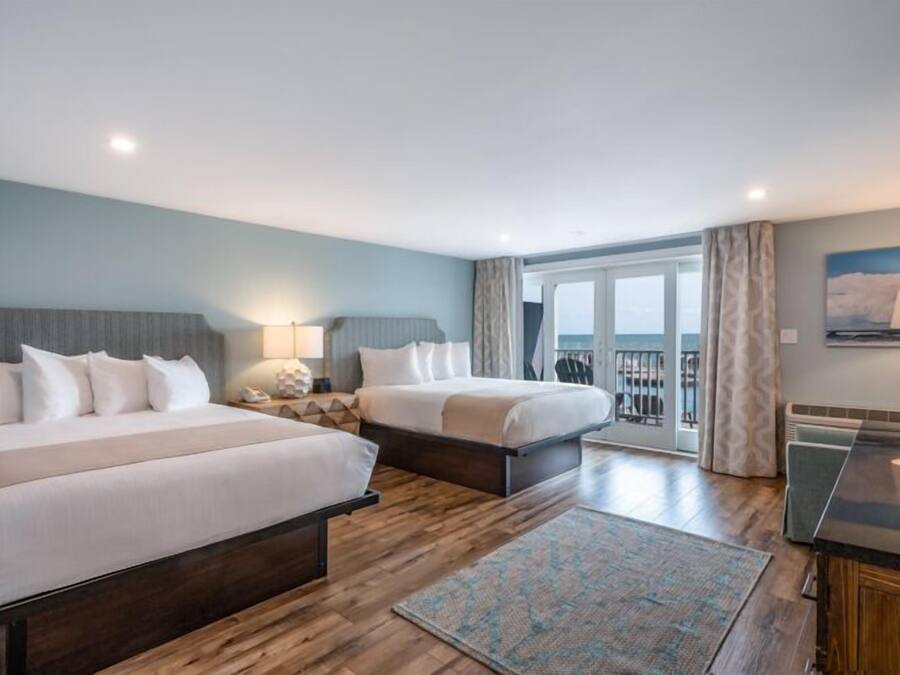 Una habitación de hotel con dos camas, un escritorio y vista al mar.