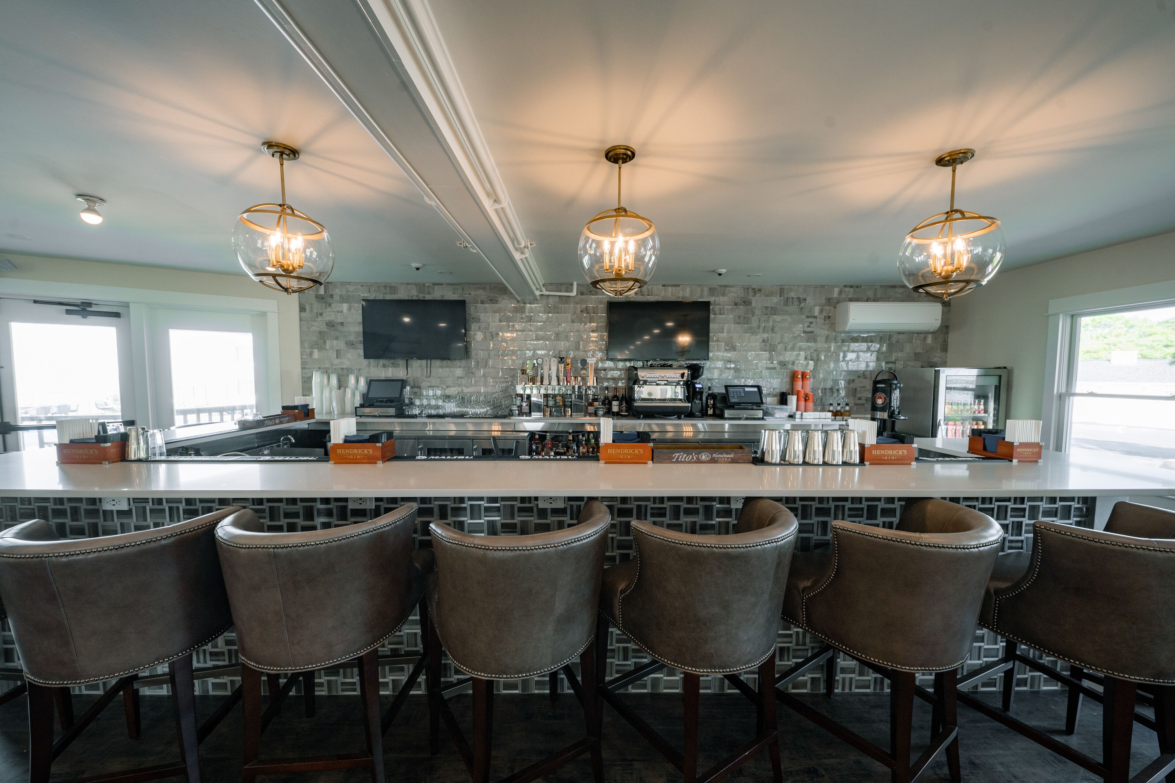 A modern kitchen with a central island, bar stools, and pendant lighting.