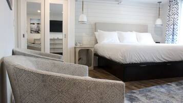 A bedroom with a large bed, a bedside table, a nightstand, and a chair.