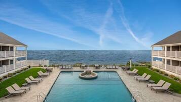 Un espace piscine avec des chaises longues et vue sur la mer.