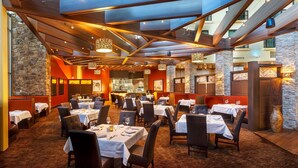 A restaurant with multiple dining tables, stone walls, and modern lighting fixtures. - Sky Ute Casino Resort (Ignacio)
